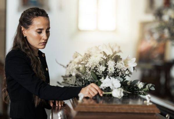 Grieving woman placing a flower on a casket at a funeral.